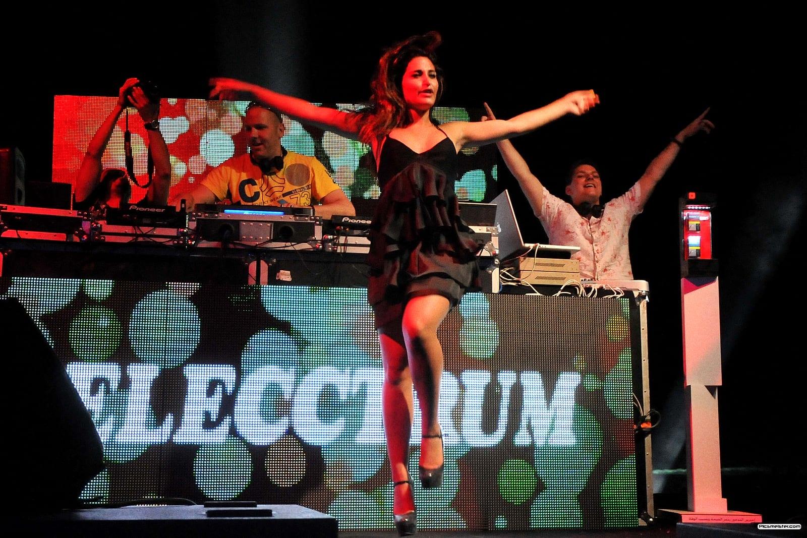 DJ booth with a dancer on top and the crowd's arms in the air