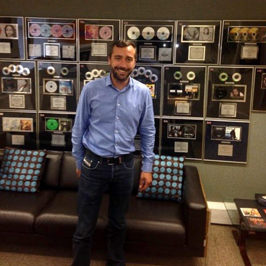 A man in front of a wall of framed gold and platinum discs